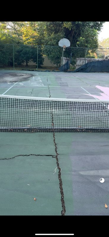 Cracked asphalt tennis court in Florida showing deep cracks from poor construction